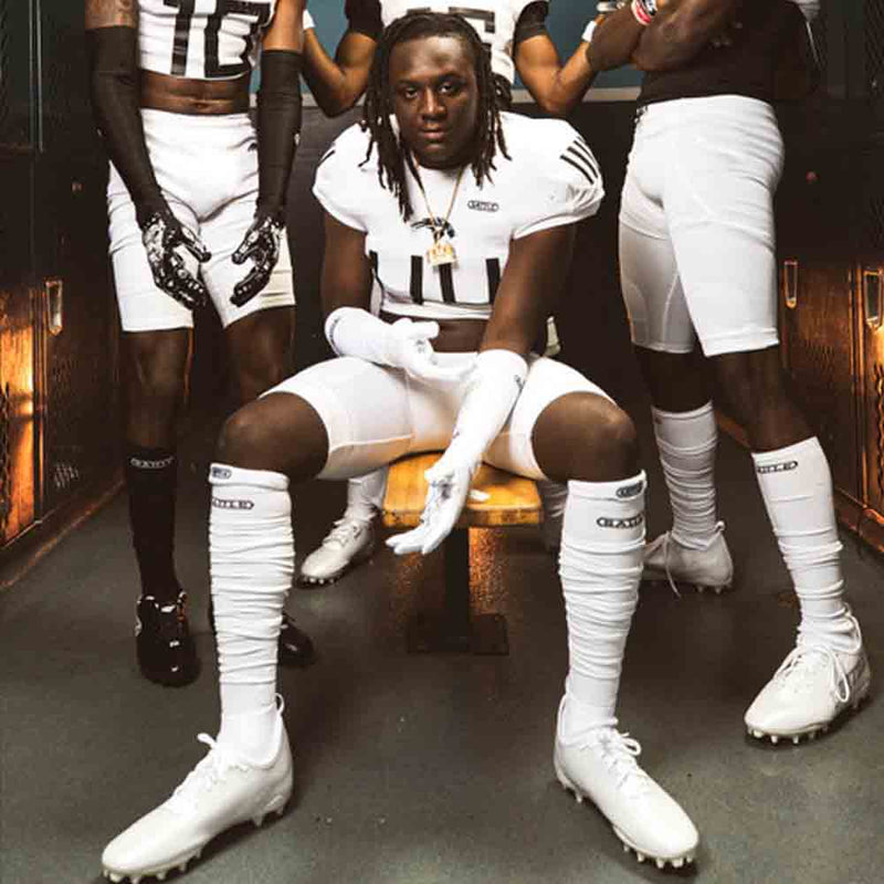 Football players wearing the Battle Adult Black Long Football Socks.